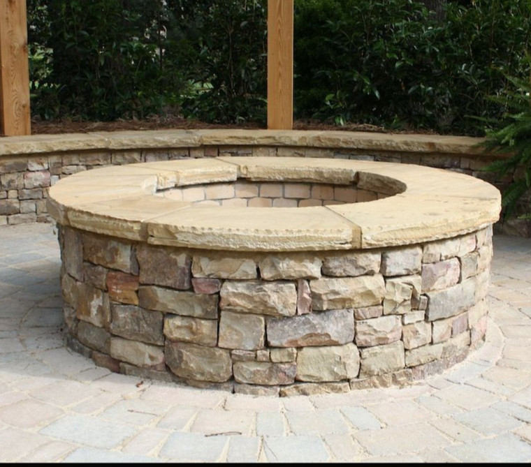 Round stacked-stone fire pit with capstone seating wall