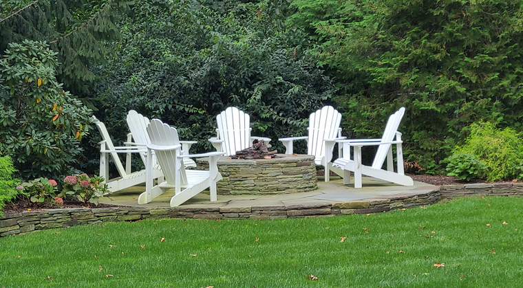 Backyard fire pit with Adirondack chairs on a stone surround