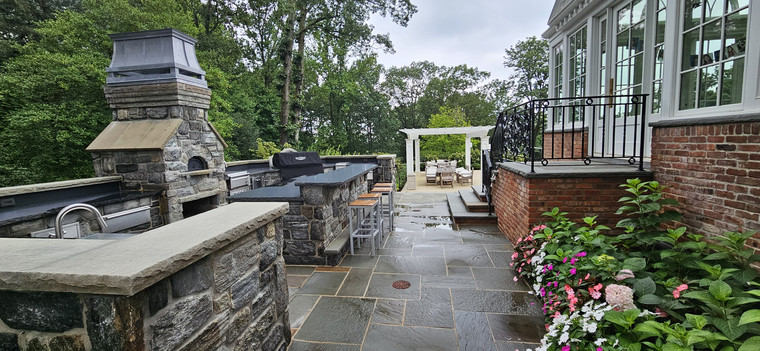 Stone outdoor kitchen with chimney pizza oven and bar seating