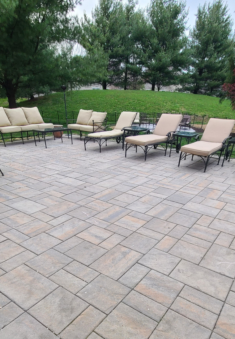 Large paver patio with lounge furniture overlooking a sloped lawn