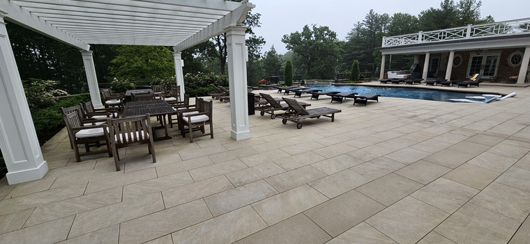 Expansive paver pool patio with pergola dining and chaise lounges