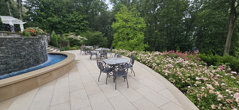 Curved patio terrace beside a water feature with garden dining sets