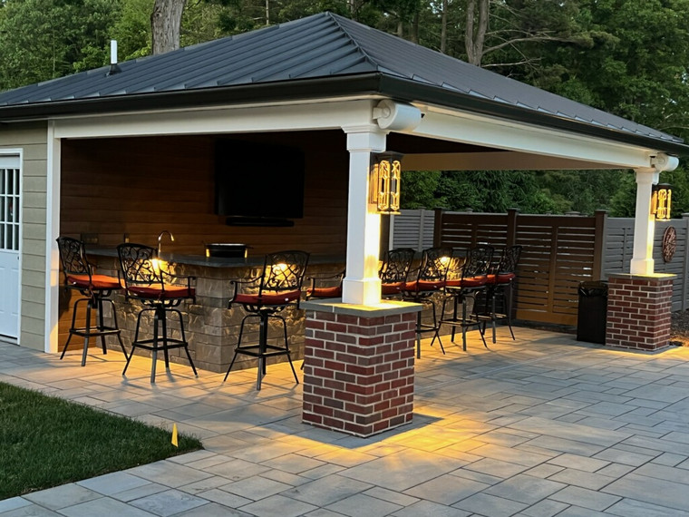 Evening-lit pavilion bar with brick columns and stone counters