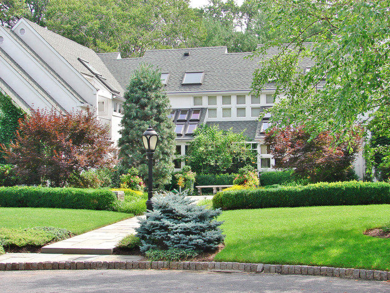 Formal estate landscape with clipped boxwood hedges and layered shade plantings